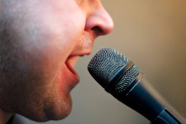 Beyaz tüylü adam mikrofon agresif tarzda rock müziği şarkı. Ağız ve mikrofon yakın çekim. Konser veya Karaoke.