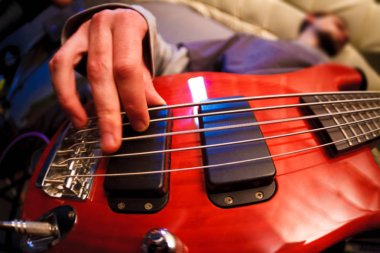 Adam kırmızı bas gitar çalıyor. Elini kapat. Seçici odaklama bokeh. Geniş açı düşük görünüm