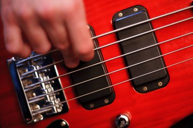 Adamın eli kırmızı bas gitar çalıyor. Seçici Focus yakın çekim bokeh.