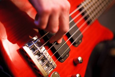 Adamın eli kırmızı bas gitar çalıyor. Seçici Focus yakın çekim bokeh.