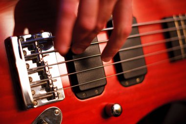Adamın eli kırmızı bas gitar çalıyor. Seçici Focus yakın çekim bokeh.