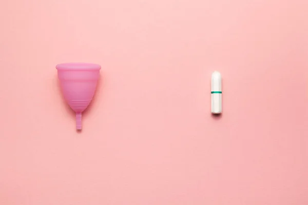Återanvändbara silikon menstruations kopp och Tampon jämförelse på en mjuk rosa bakgrund. Modern kvinnlig intim alternativ gynekologisk hygien. Eco Zero avfall koncept. Royaltyfria Stockfoton