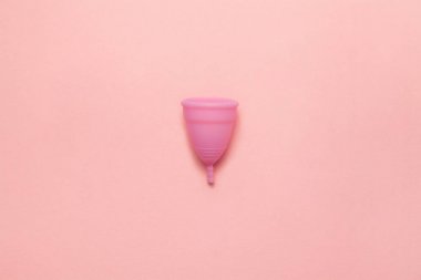 Yumuşak pembe arka planda yeniden kullanılabilir silikon menstrüel fincan. Modern kadın samimi alternatif jinekolojik hijyen. Eko sıfır atık kavramı. Metin için yer yeri kopyalayın. Düz yatma