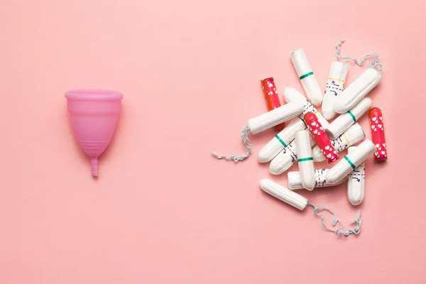 Återanvändbara silikon menstruations cupen och högen av tamponger jämförelse på en mjuk rosa bakgrund. Modern kvinnlig intim alternativ gynekologisk hygien. Eco Zero avfall koncept — Stockfoto