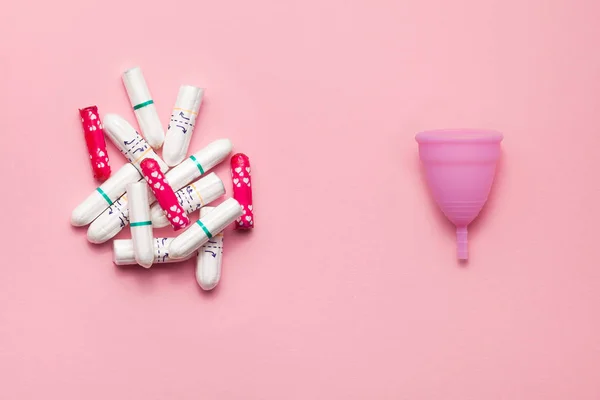Reusable silicone menstrual cup and heap of tampons comparison on a soft pink background. Modern female intimate alternative gynecological hygiene. Eco zero waste concept — Stock Photo, Image