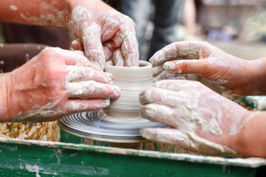 Çömlekçilik yakın. Romantik Çift ortakları bir kil pot yapmaya çalışırken onların boş harcama. Diğerlerinin elleri bir tekerleğe yardım etmek için başkalarına rehberlik