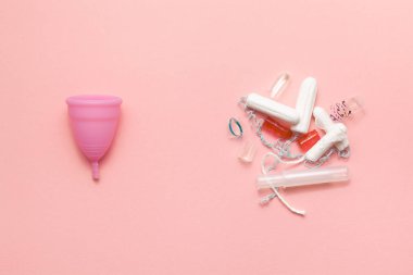 Yeniden kullanılabilir silikon menstrüel fincan ve tampon yığını yumuşak pembe arka planda çöp karşılaştırma. Modern kadın samimi alternatif jinekolojik hijyen. Eko sıfır atık kavramı