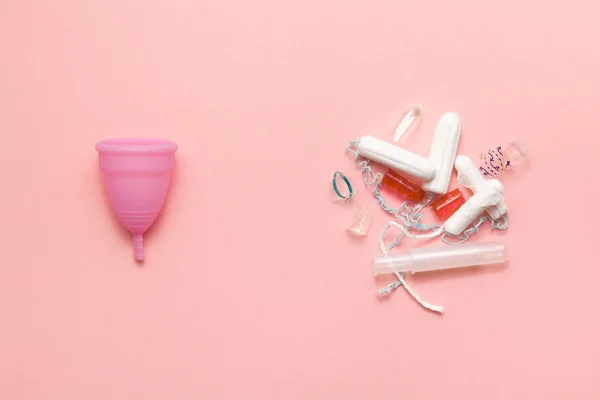 재사용 가능한 실리콘 생리컵과 탐폰 더미가 부드러운 분홍색 배경에 쓰레기 를 비교합니다. 현대 여성 친밀한 대체 부인과 위생. 에코 제로 폐기물 개념 — 스톡 사진