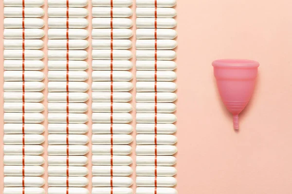 Återanvändbara silikon menstruations cupen och högen av tamponger jämförelse på en mjuk rosa bakgrund. Modern kvinnlig intim alternativ gynekologisk hygien. Eco Zero avfall koncept — Stockfoto