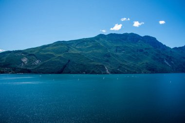 Mavi gökyüzü, yelkenli tekneler ve Trentino Alto Adige 'in yemyeşil dağları ile Ponale Yolu' ndan güzel Garda Gölü manzarası.