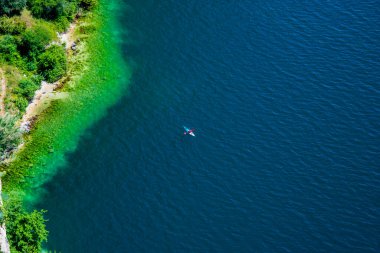 Bir kano, güneşli bir yaz gününde İtalya, Trento, Riva del Garda 'da, Garda gölünün durgun mavi sularında sessizce yüzer.