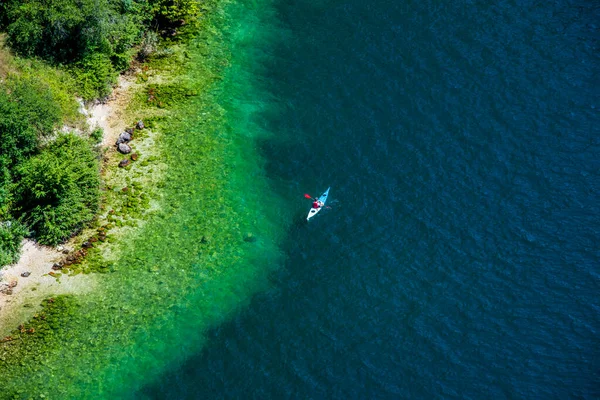 Bir kano, güneşli bir yaz gününde İtalya, Trento, Riva del Garda 'da, Garda gölünün durgun mavi sularında sessizce yüzer.