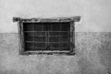 Paslı parmaklıklı pencere ve beyaz duvarlı eski ahşap çerçeve