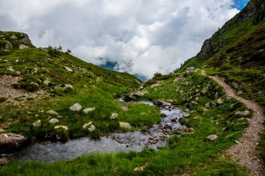 İtalya 'nın Trento kentinde Levico Gölü yakınlarındaki Lagorai' nin alp ve granit kayalıkları üzerindeki yeşil çayırlar arasında akarsu huzur içinde akar.