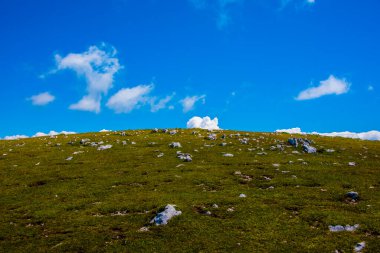 Monte Altissimo di Nago 'nun tepesinde arka planda kayalar ve çayırlar ile mavi gökyüzü ve İtalya Trento' da beyaz bulutlar