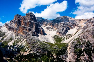 Beyaz bulutlu mavi gökyüzü, İtalya 'nın Belluno, Veneto kentindeki Cortina D' ampezzo Dolomites 'in pembe tepelerini sarar.