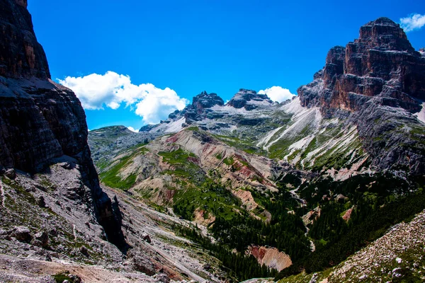 Beyaz bulutlu mavi gökyüzü, İtalya 'nın Belluno, Veneto kentindeki Cortina D' ampezzo Dolomites 'in pembe tepelerini sarar.
