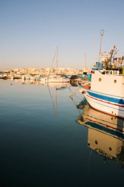 Marsaxlokk, Malta, Ağustos 2019. Şehrin arka planda büyük balıkçı teknesi, dikey versiyonu. 