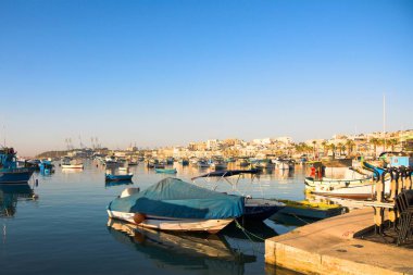 Marsaxlokk, Malta, Ağustos 2019. Sabahın erken saatlerinde şehir merkezinde park etmiş tekneler ve diğer gemiler.