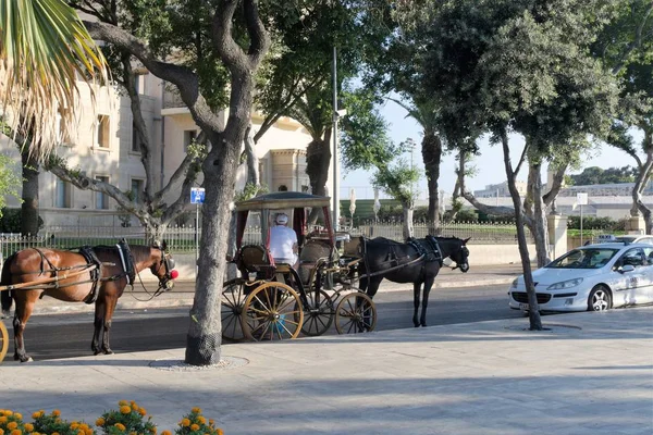 Valletta, Malta, Ağustos 2019. Modern taksi ve at arabaları lüks bir otelin yakınında..