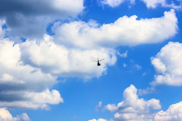 Bulutların arasında mavi gökyüzünde uçan helikopter..