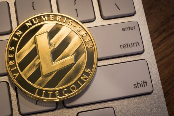 Close up new gold Litecoins with light reflex, coin put on modern keyboard that show enter, return and shift buttons. Concepts for cryptocurrency blockchain, trading and money exchange.