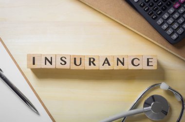 Düz yatıyordu, tablo üstten görünüm haber sigorta küpleri stetoskop, dizüstü bilgisayarlar, evrak, ahşap Resepsiyon arka plan ile. Sağlık Politikası, güvenlik, kişisel güvenlik planı, iş yatırım kavramları.