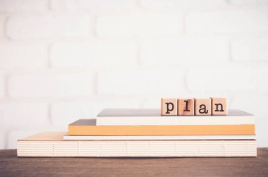 PLAN sözcüğü, tahta küplerin üstündeki harfler tuğla kaplamalı masa arkaplan, boş fotokopi alanı, asgari düzeyde. Hedef belirleme kavramları, proje yönetimi, mali bütçe.