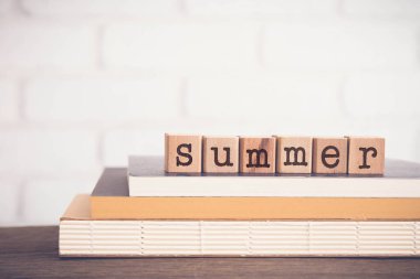 SuMER kelimesi, kitapların üstündeki blok küplere yazılmış harfler ve beyaz tuğlalı ahşap masa, boş fotokopi alanı, klasik asgari tarz. Mevsim, hava, tatil ve yaşam tarzı kavramları.