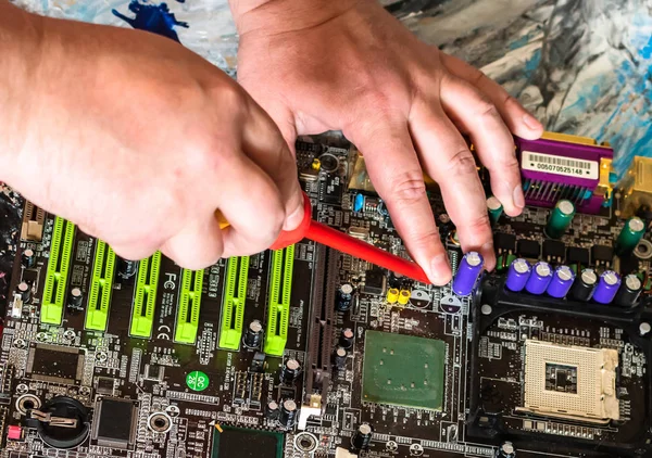 Repair of a PC motherboard with a screwdriver with a red handle