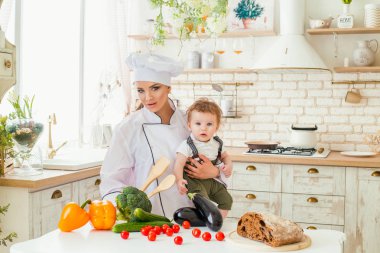 Genç bir anne oğluyla bir aile yemeği hazırlarken mutfaktaki,