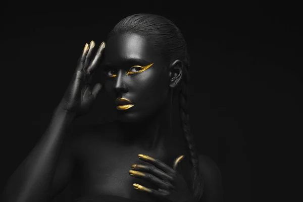 Siyah arka planda altından yapılmış parlak makyajlı güzel bir kadın.