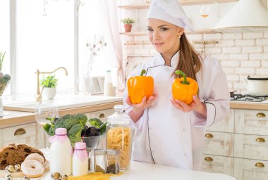 kadın şef mutfakta, masaya yiyecek bolluğu