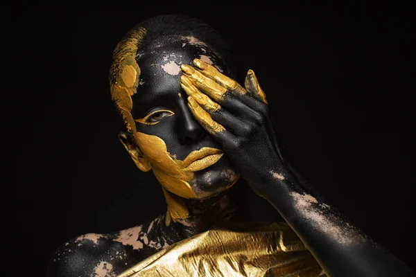 portrait of a beautiful and young woman with gold paint on her body