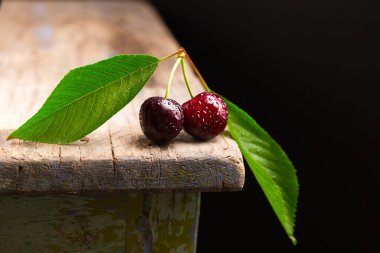 Tahta bir masanın kenarında iki kiraz.