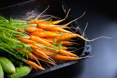 Arka planda salatalıklı küçük havuçlar, bahçeden taze sebzeler.