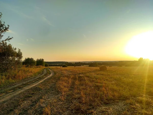 Venkovská Silnice Prochází Poli Opuštěnou Vesnicí Vchází Zapadajícího Slunce — Stock fotografie