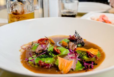 deniz ürünleri ve kurutulmuş domates parçaları ile et suyu ravioli yeşil