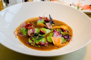 deniz ürünleri ve kurutulmuş domates parçaları ile et suyu ravioli yeşil