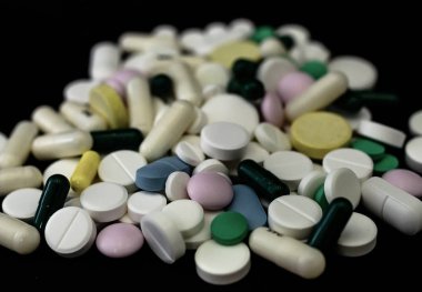 Kavanozdan siyah bir arka plan üzerine dökülen tıbbi tabletler.