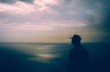 Gün batımında sahilde duran adam.