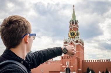 Moskova'daki Kremlin'in Spassky Kulesi'nin saatini karşılaştıran saatli bir adamın eli.
