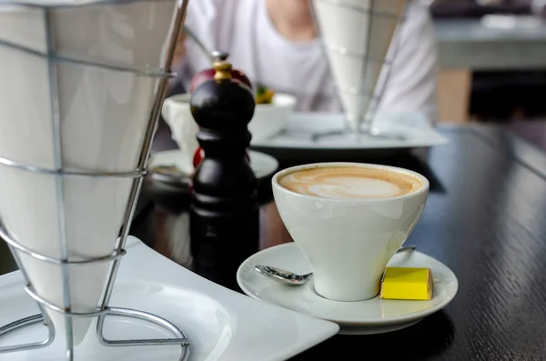 Eine Tasse Kaffee auf dem Tisch im Restaurant. Schokolade auf der Untertasse mit Kaffee — Stockfoto