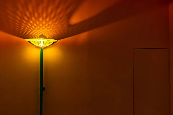 The lamp in an empty room with the included light. Abstract photo with a burning lamp in an empty room. Background picture