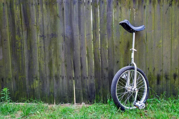 Unibike (monocycle) standing against wooden fence background — Stock Photo, Image