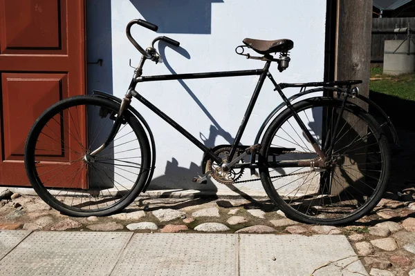 Bicicleta preta vintage estacionada fora da casa velha com porta de madeira , — Fotografia de Stock