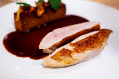 medium rare goose breast steak with brown gravy served on a white plate in a fancy restaurant