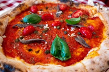 traditional italian pizza napoli - margherita with anchovy tomato sauce and basil leaves