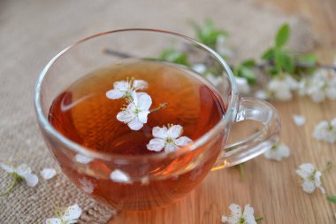 Çiçeklerle ahşap bir masada bir fincan çay.