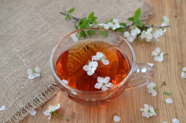 Çiçeklerle ahşap bir masada bir fincan çay.